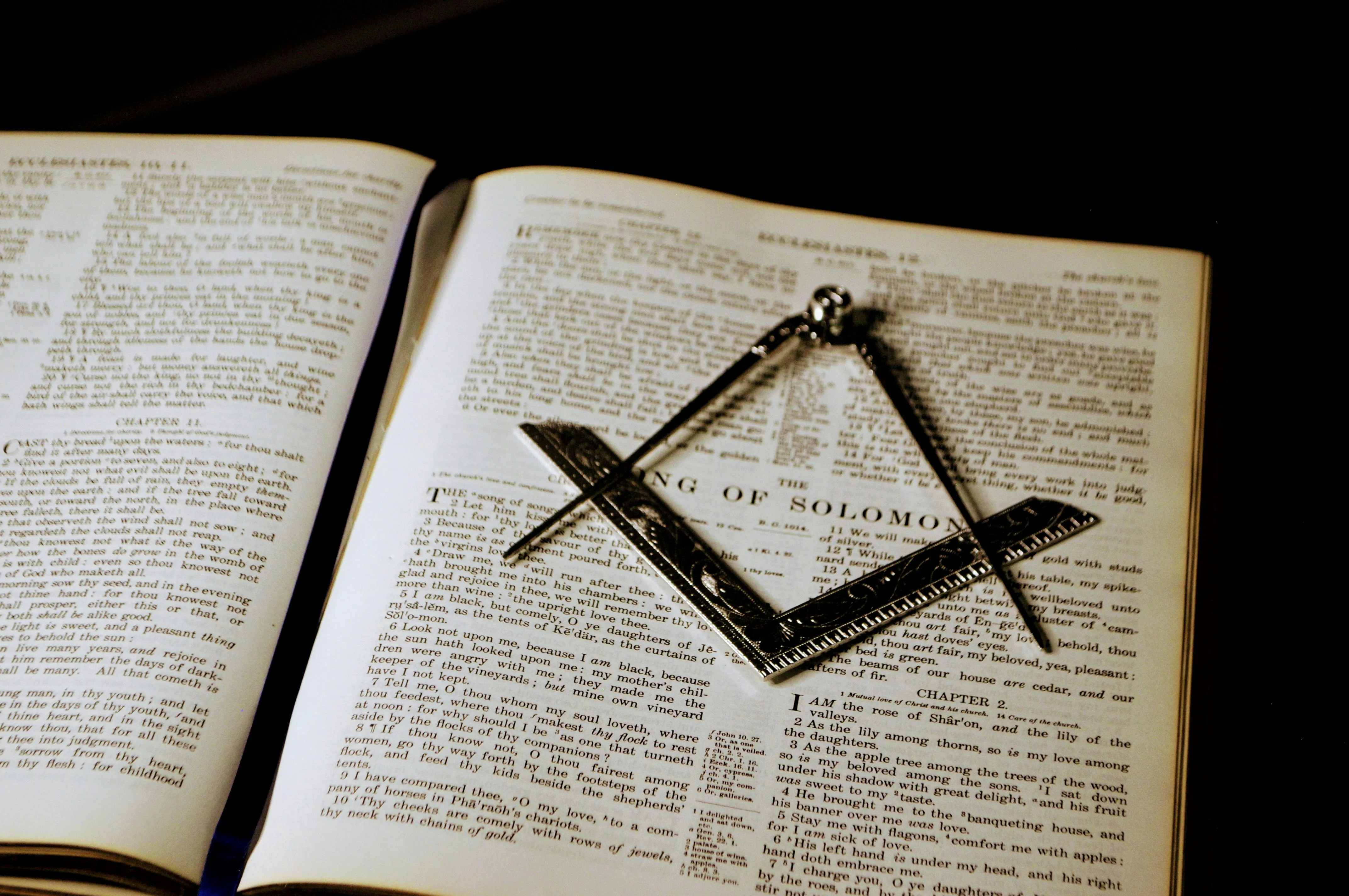 Square and compasses resting on an open volume of sacred law